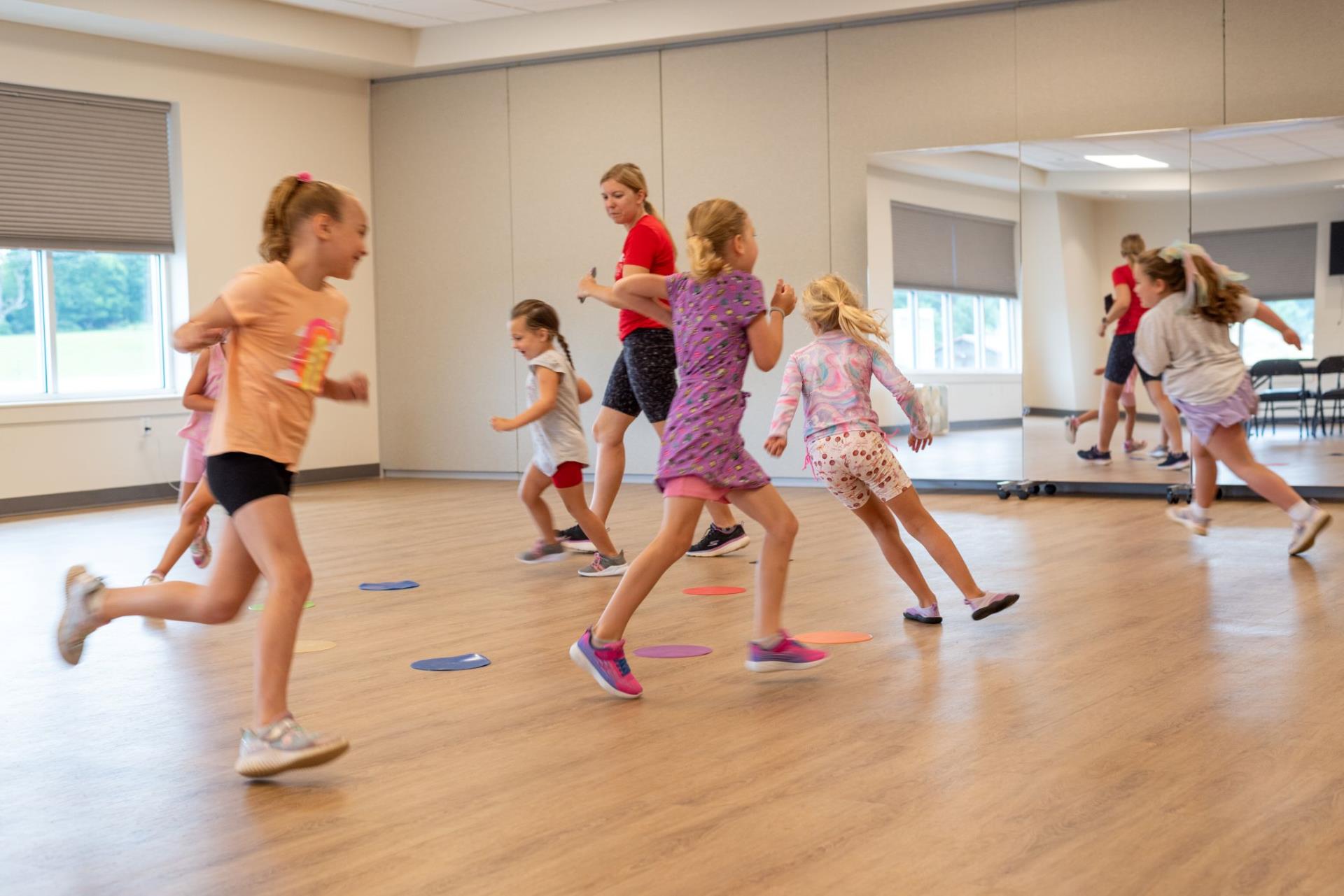 Children running around in a circle as part of a Cheerleading class warm up exercise.