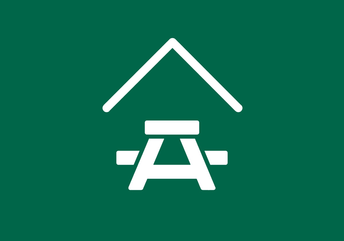 white shelter and picnic table icon on green background